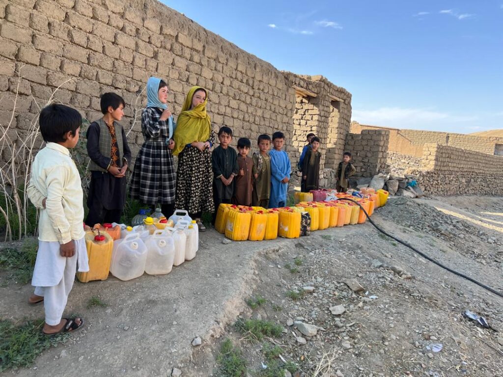 Children beside rows of water jerrycans in Ghor