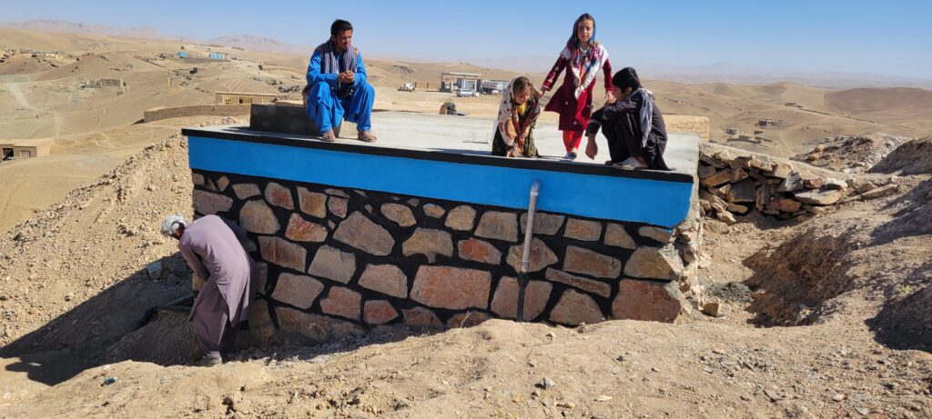 A family at the finished reservoir and tap